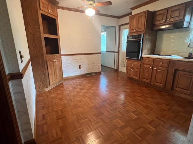 kitchen with wallpapered walls, oven, ornamental molding, baseboards, and ceiling fan