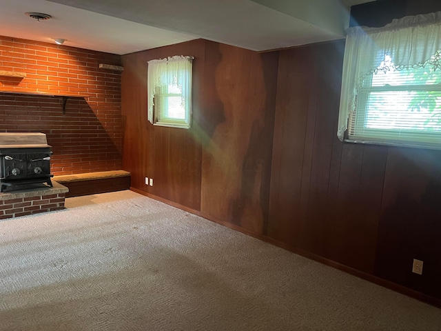 unfurnished living room with a wood stove, carpet floors, and wood walls