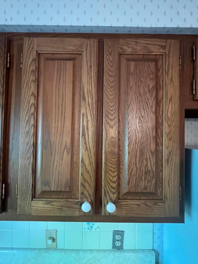 kitchen view of wallpapered walls and brown cabinets