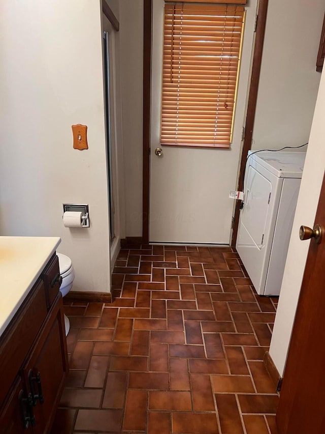 laundry area featuring washer / dryer, brick patterned flooring, and baseboards
