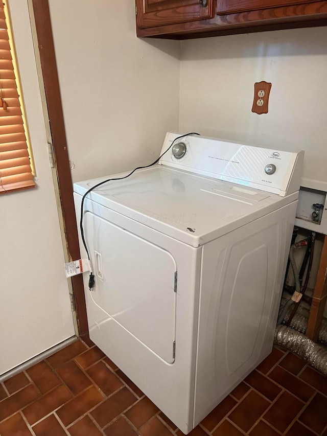 laundry area featuring washer / dryer, brick patterned flooring, and cabinet space