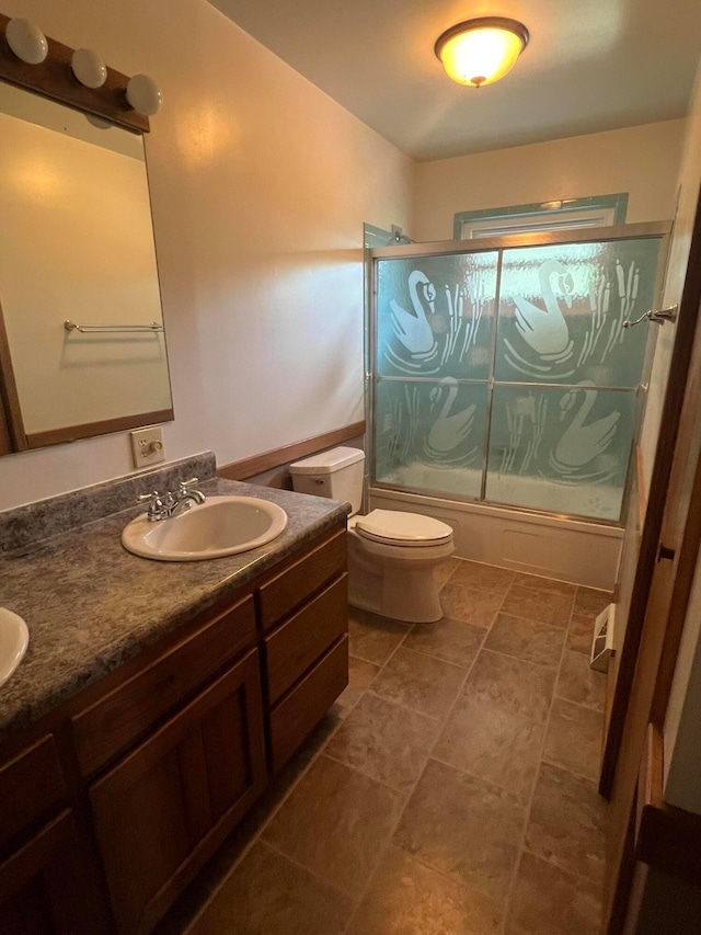 bathroom featuring enclosed tub / shower combo, toilet, and double vanity