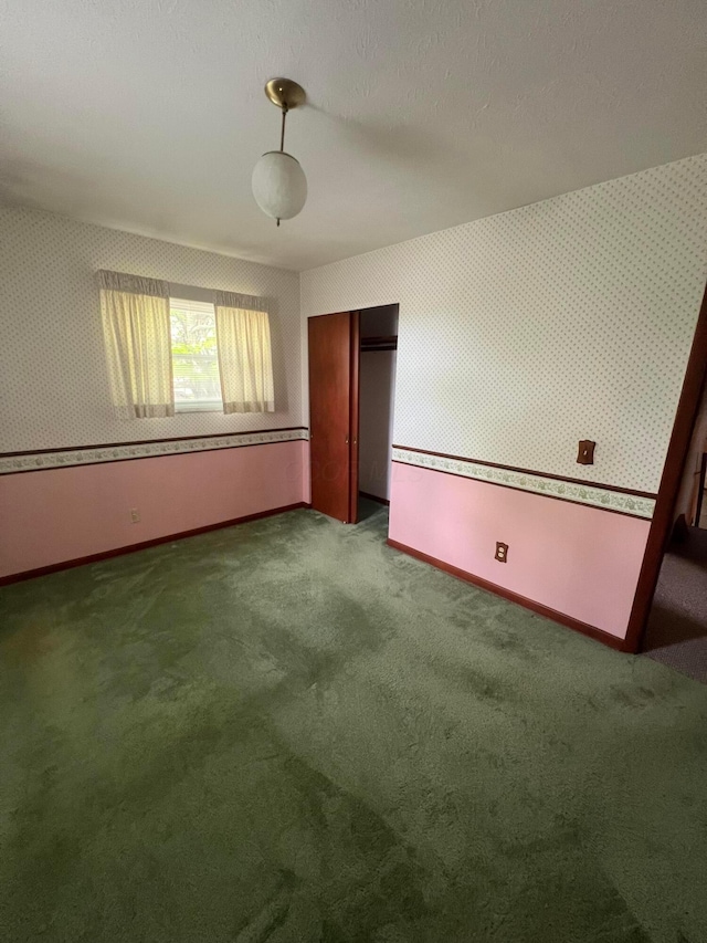 unfurnished bedroom with baseboards, a closet, carpet flooring, and wallpapered walls