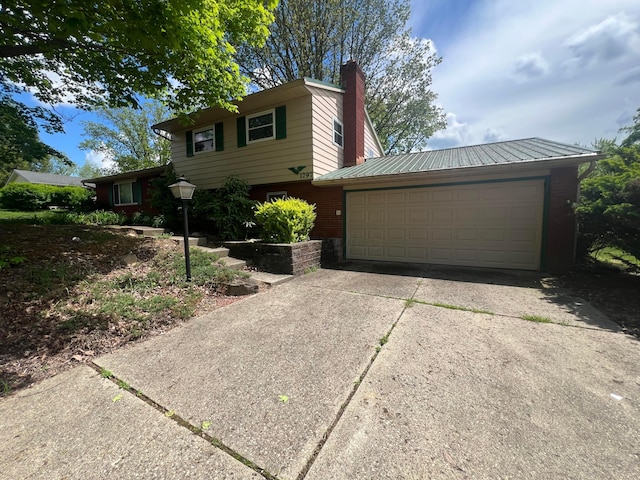 view of front facade featuring a chimney, concrete driveway, and an attached garage