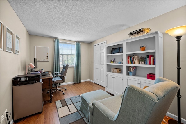 home office with wood finished floors, a textured ceiling, and baseboards