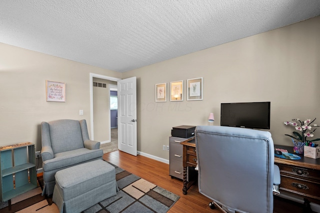 office featuring wood finished floors, a textured ceiling, and baseboards