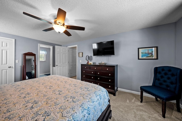 bedroom featuring light carpet, baseboards, a textured ceiling, and ceiling fan