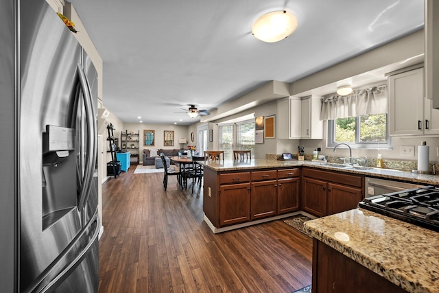 kitchen with stainless steel refrigerator with ice dispenser, a peninsula, a sink, dark wood finished floors, and open floor plan