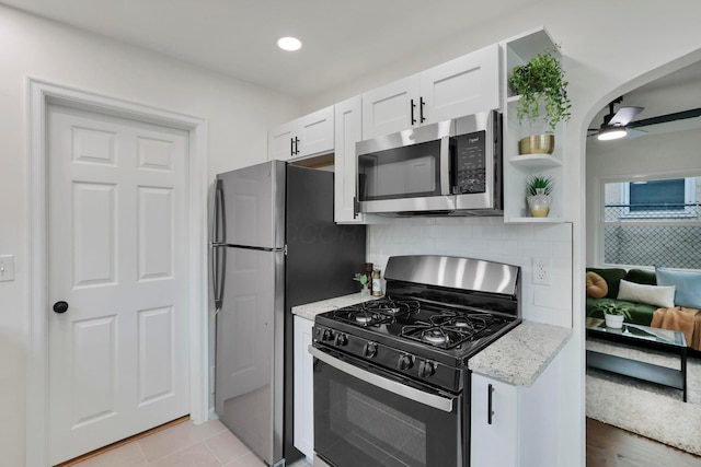 234 Rosslyn Ave, Columbus, OH 43214 - kitchen with stainless steel appliances, white cabinetry, light stone counters, tasteful backsplash, and ceiling fan