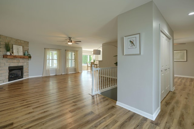 1899 Lamb Rd NW, Carroll, OH 43112 - unfurnished living room featuring a ceiling fan, wood finished floors, a stone fireplace, and baseboards