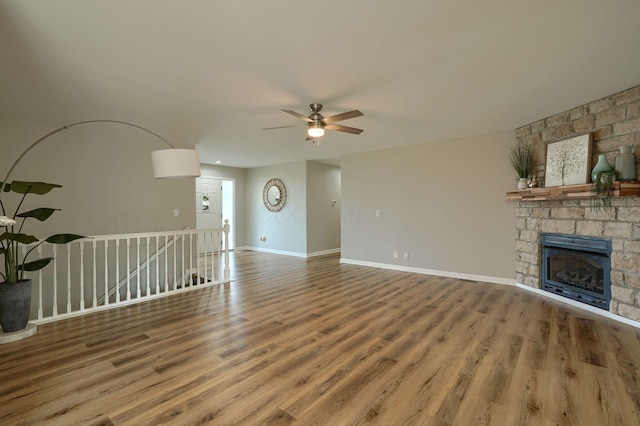 1899 Lamb Rd NW, Carroll, OH 43112 - unfurnished living room featuring ceiling fan, wood finished floors, a stone fireplace, and baseboards