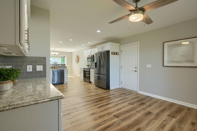 1899 Lamb Rd NW, Carroll, OH 43112 - kitchen with stainless steel appliances, light wood finished floors, white cabinets, decorative backsplash, and baseboards