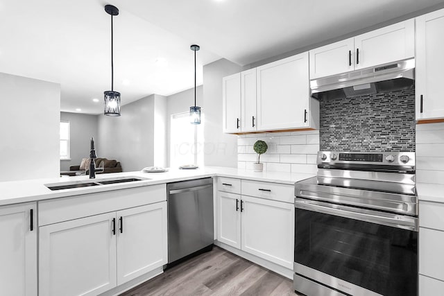 527 E Welch Ave, Columbus, OH 43207 - kitchen featuring stainless steel appliances, under cabinet range hood, white cabinets, light countertops, and decorative backsplash