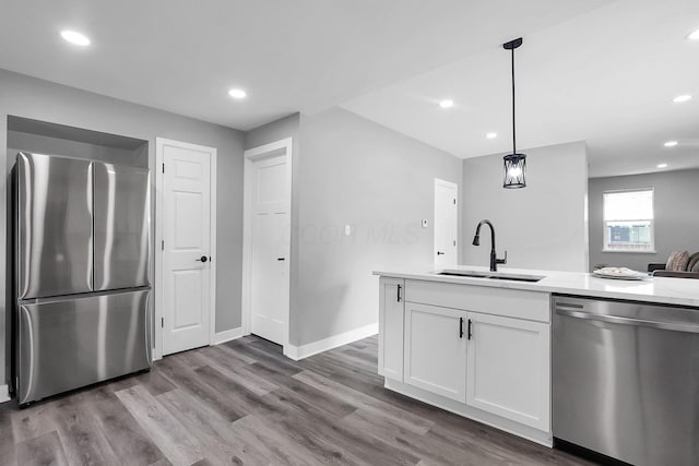 527 E Welch Ave, Columbus, OH 43207 - kitchen with appliances with stainless steel finishes, a sink, white cabinets, light countertops, and wood finished floors