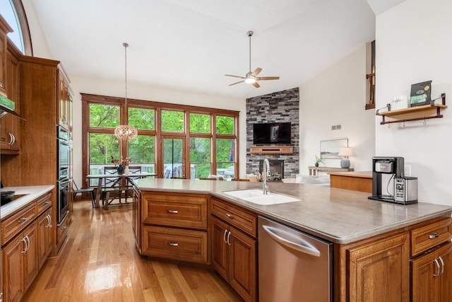 kitchen featuring appliances with stainless steel finishes, a sink, lofted ceiling, light wood-style floors, and a ceiling fan