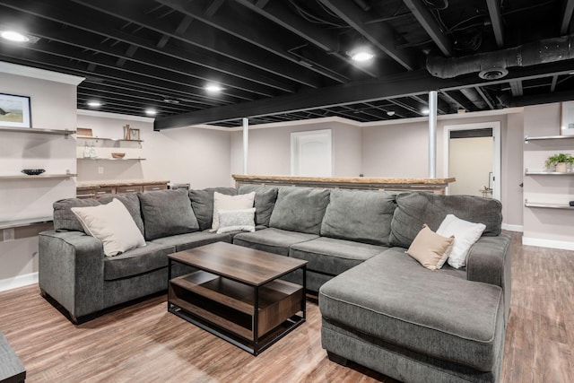 living room featuring baseboards, light wood-style flooring, and bar area