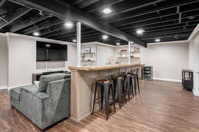 indoor wet bar featuring beverage cooler, baseboards, and wood finished floors