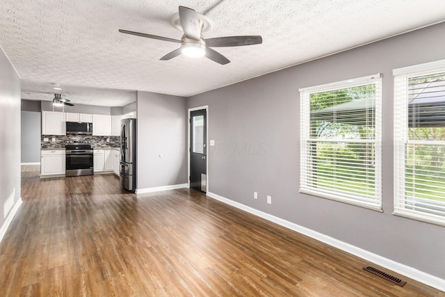 1279 Reana Dr, Galloway, OH 43119 - unfurnished living room featuring a ceiling fan, baseboards, dark wood-style flooring, and a textured ceiling