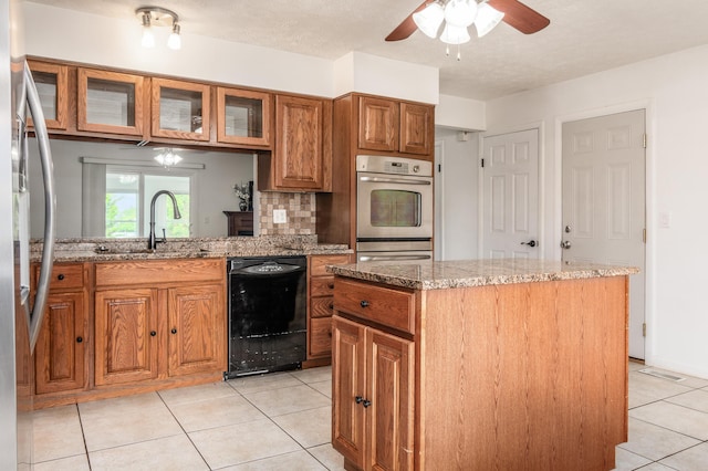 717 Birmingham Rd, Westerville, OH 43081 - kitchen featuring stainless steel appliances, brown cabinetry, light tile patterned floors, ceiling fan, and light stone counters