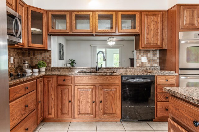 717 Birmingham Rd, Westerville, OH 43081 - kitchen with black appliances, a sink, brown cabinets, light stone countertops, and backsplash