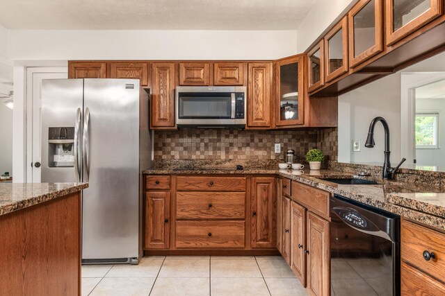 717 Birmingham Rd, Westerville, OH 43081 - kitchen with stainless steel appliances, a sink, brown cabinetry, dark stone counters, and decorative backsplash
