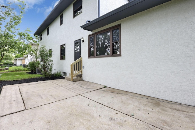 1883 Fairhaven Rd, Columbus, OH 43229 - view of property exterior featuring entry steps, stucco siding, a patio area, and central air condition unit