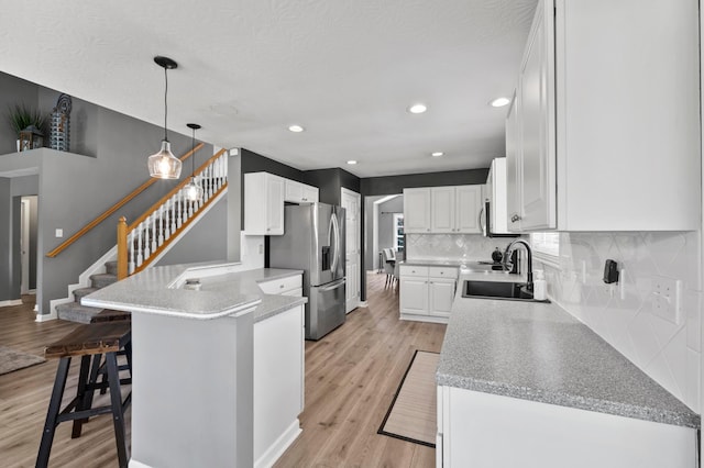 4008 Ryleland Ct, Powell, OH 43065 - kitchen with stainless steel fridge, a peninsula, white cabinets, backsplash, and recessed lighting