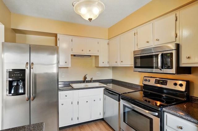 662 Pamlico St Unit Z7, Columbus, OH 43228 - kitchen with appliances with stainless steel finishes, a sink, dark countertops, light wood-style floors, and white cabinetry