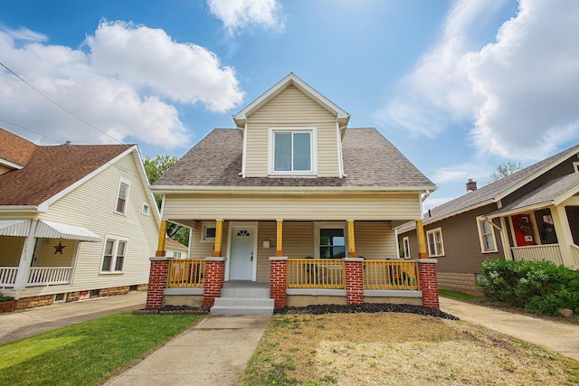 bungalow-style house with covered porch, roof with shingles, and a front yard