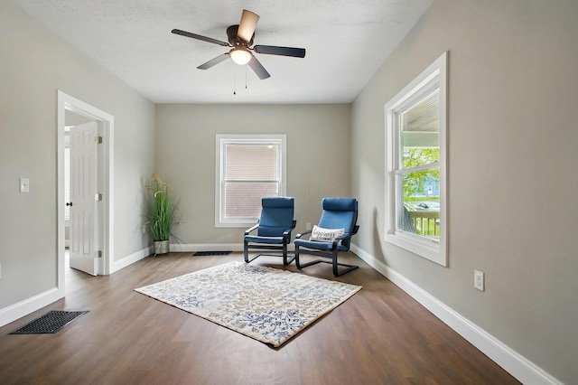 living area featuring wood finished floors, ceiling fan, and baseboards