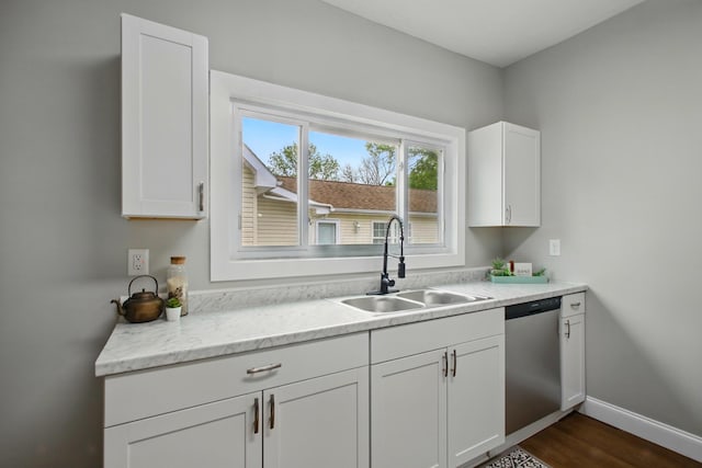 kitchen with dishwasher, a sink, white cabinets, dark wood-style flooring, and baseboards