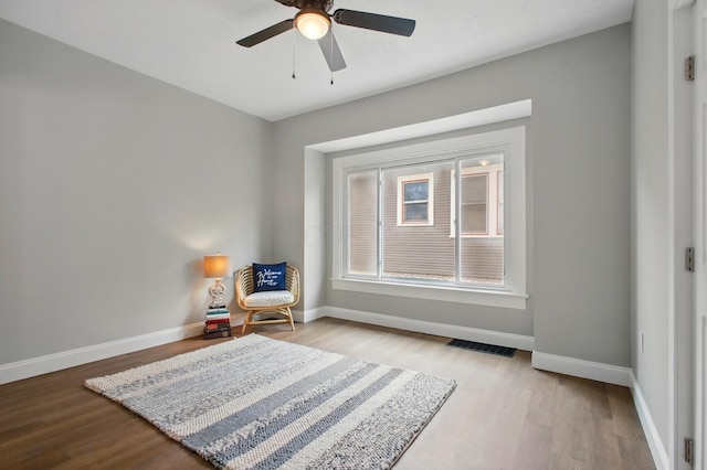 sitting room with ceiling fan, wood finished floors, and baseboards