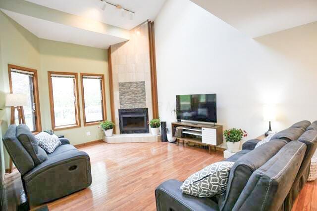 532 Woodview Rd, Westerville, OH 43081 - living room with rail lighting, wood finished floors, a tiled fireplace, and high vaulted ceiling