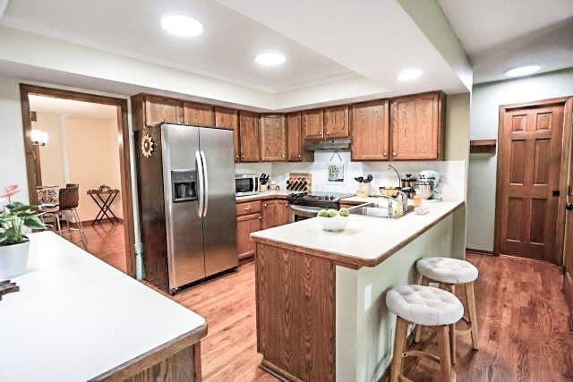 532 Woodview Rd, Westerville, OH 43081 - kitchen with stainless steel appliances, under cabinet range hood, a breakfast bar, brown cabinets, and light countertops