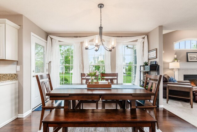 4381 Grathrine Ct, Lewis Center, OH 43035 - dining room featuring a chandelier, dark wood-type flooring, a lit fireplace, and baseboards