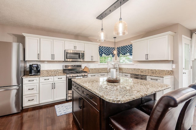 4381 Grathrine Ct, Lewis Center, OH 43035 - kitchen featuring appliances with stainless steel finishes, dark wood finished floors, white cabinets, a breakfast bar area, and decorative light fixtures