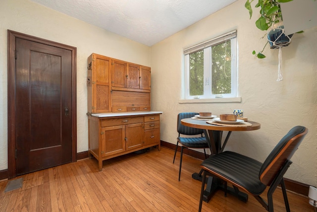 651 Eastern Ave, Bellefontaine, OH 43311 - dining space featuring light wood-style flooring, baseboards, a textured ceiling, and a textured wall