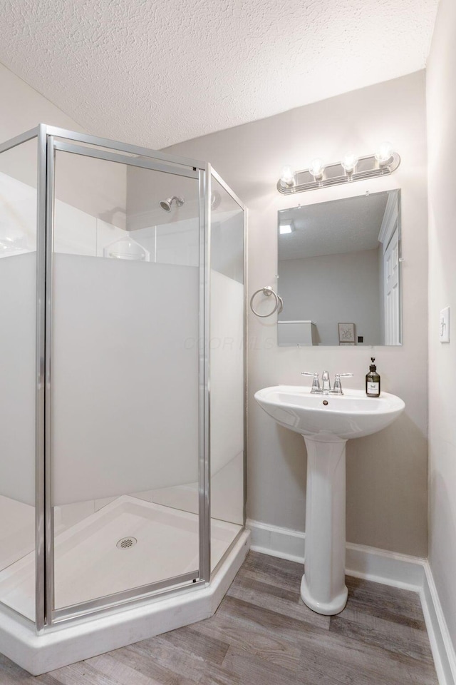 581 Kelton Ave, Columbus, OH 43205 - full bathroom featuring wood finished floors, a stall shower, baseboards, a textured ceiling, and a sink