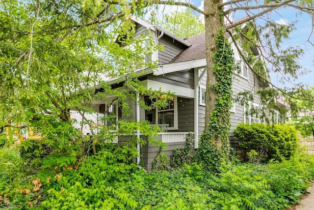 view of side of property with covered porch and fence