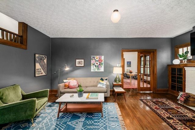 living area with wood finished floors, baseboards, a textured ceiling, and french doors