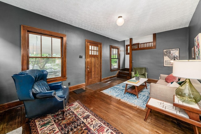 living room featuring wood finished floors, a textured ceiling, and baseboards