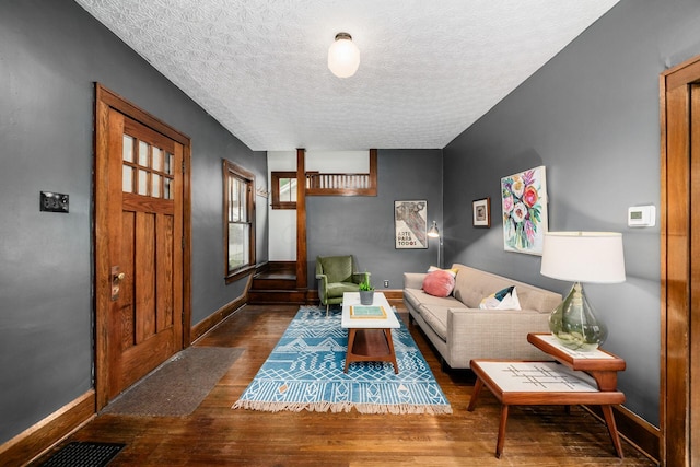 living area with wood finished floors, a textured ceiling, and baseboards