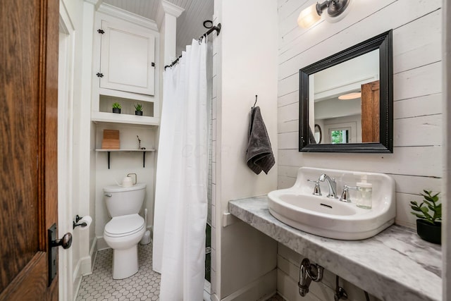 full bath with a sink, toilet, wood walls, and tile patterned flooring
