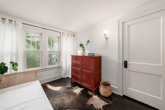 bedroom with dark wood-style floors, baseboards, and ornamental molding