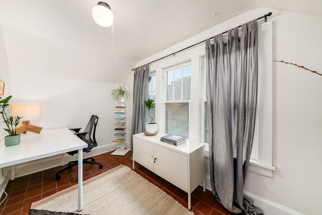 office area featuring lofted ceiling, baseboards, and dark tile patterned flooring