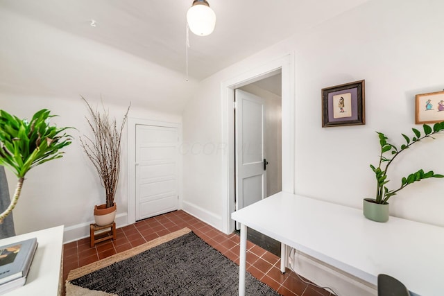 entryway with dark tile patterned flooring and baseboards