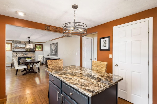 3690 Christopher Pl, Grove City, OH 43123 - kitchen featuring a chandelier, wood finished floors, a kitchen island, and a fireplace
