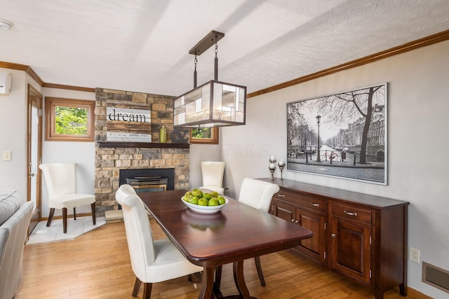 3690 Christopher Pl, Grove City, OH 43123 - dining space with light wood finished floors, a fireplace, crown molding, a textured ceiling, and baseboards