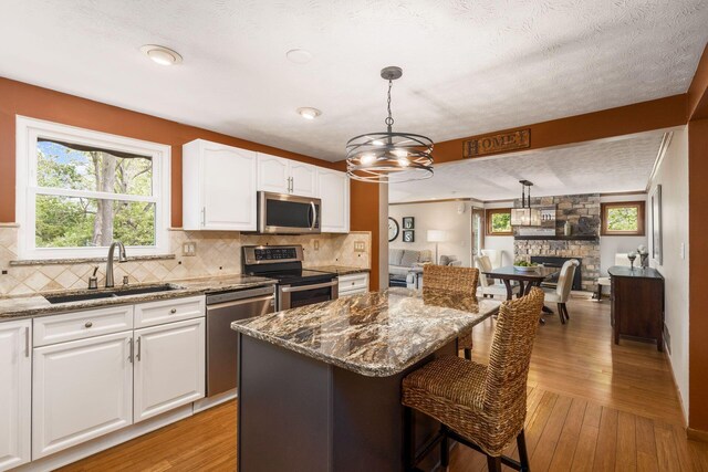 3690 Christopher Pl, Grove City, OH 43123 - kitchen with appliances with stainless steel finishes, a sink, light stone countertops, white cabinets, and a textured ceiling