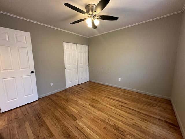 3128 Parsons Ave, Columbus, OH 43207 - unfurnished bedroom with baseboards, wood finished floors, ornamental molding, ceiling fan, and a closet